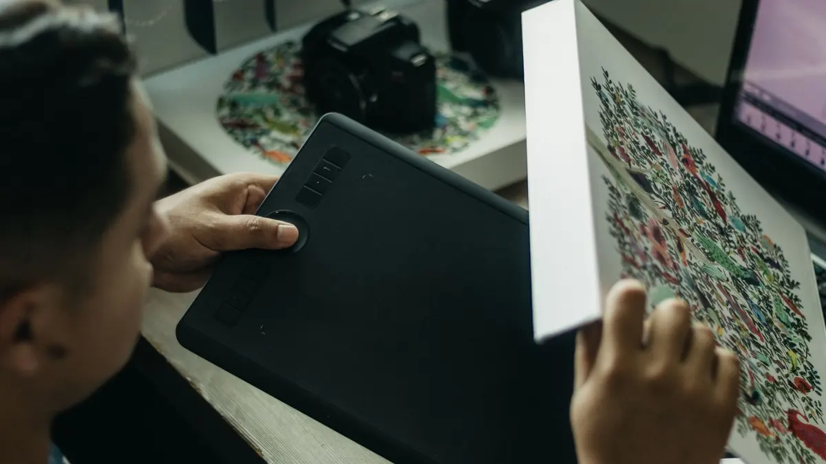 Close-up of a digital artist working with a graphics tablet indoors.