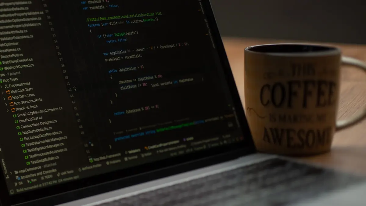 Close-up of a laptop screen with code and a coffee mug, perfect for tech abstract themes.