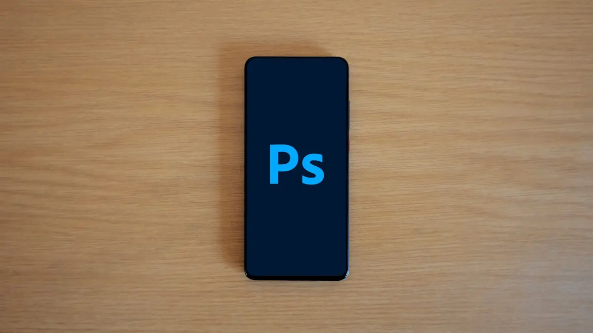Top view of a smartphone showing Adobe Photoshop on a wooden surface.