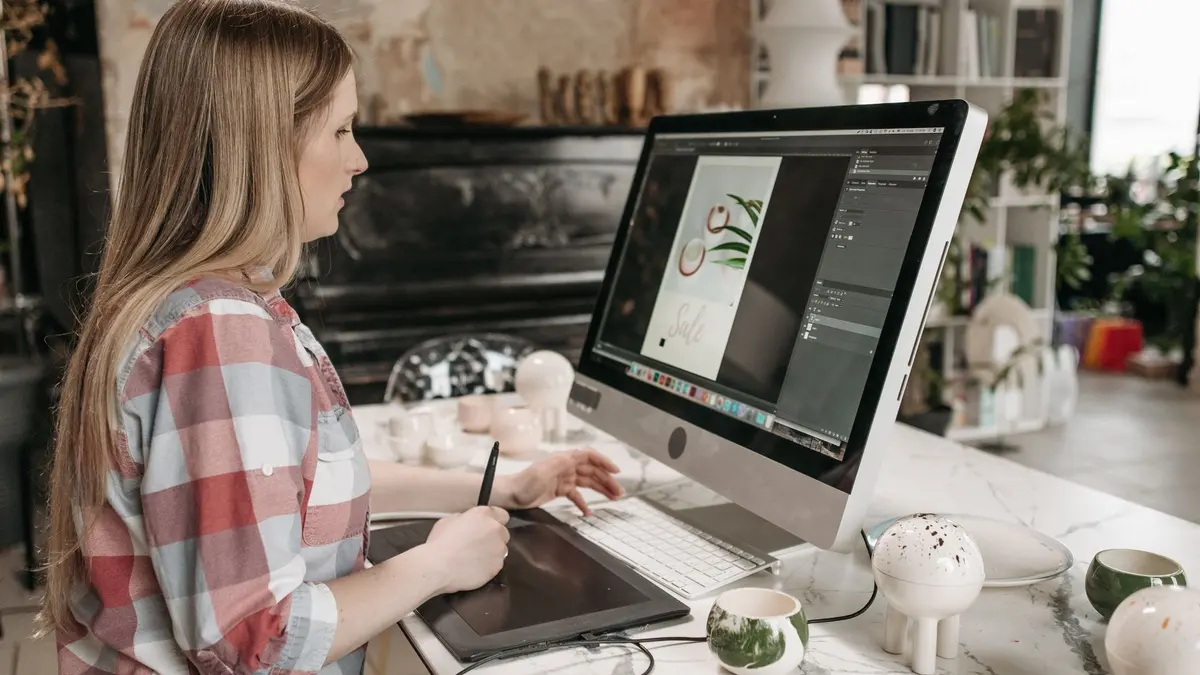 Woman using a digital drawing tablet in a stylish office workspace, focused on graphic design.